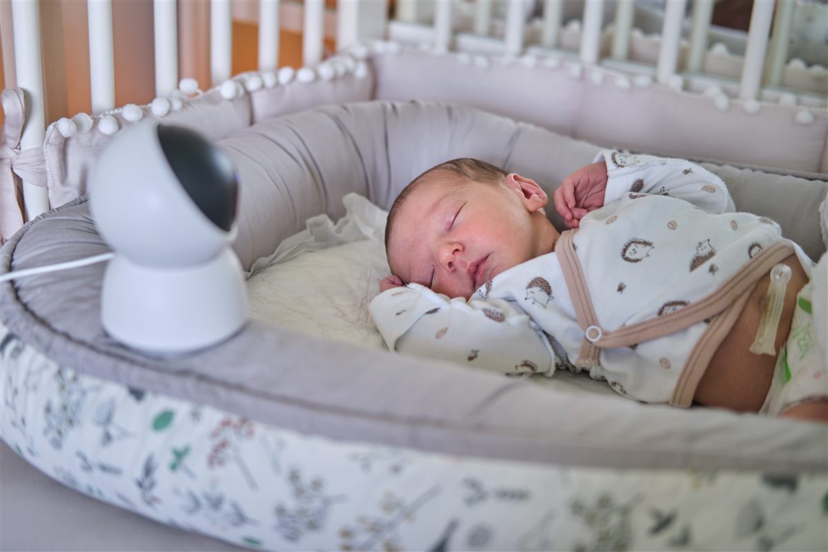 Bebé a dormir no berço com um dispositivo por perto, exemplo de quando o volume do ruído branco exige cuidado redobrado