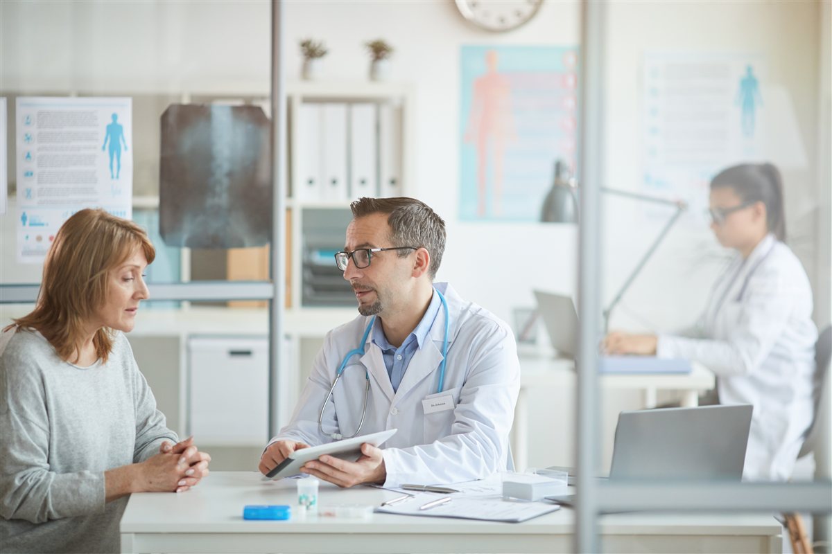 Médico a conversar com uma doente numa consulta, ambiente calmo, a explicar o processo de avaliação de um problema de sono