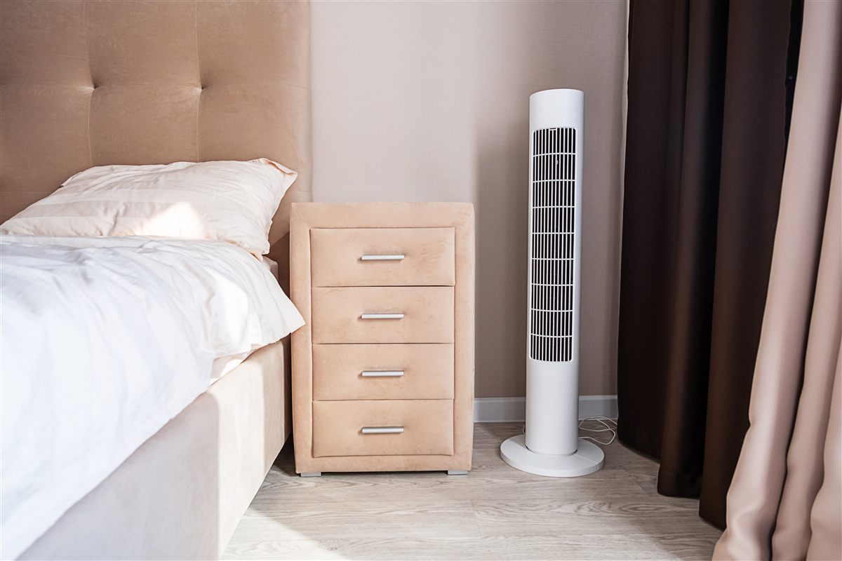 Quarto moderno com uma ventoinha de coluna junto à cama, uma das formas mais simples de gerar ruído branco